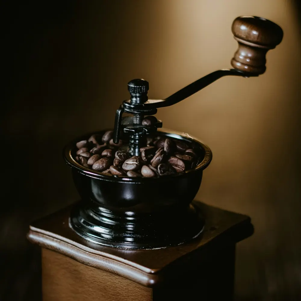Vintage hand-crank coffee grinder filled with coffee beans